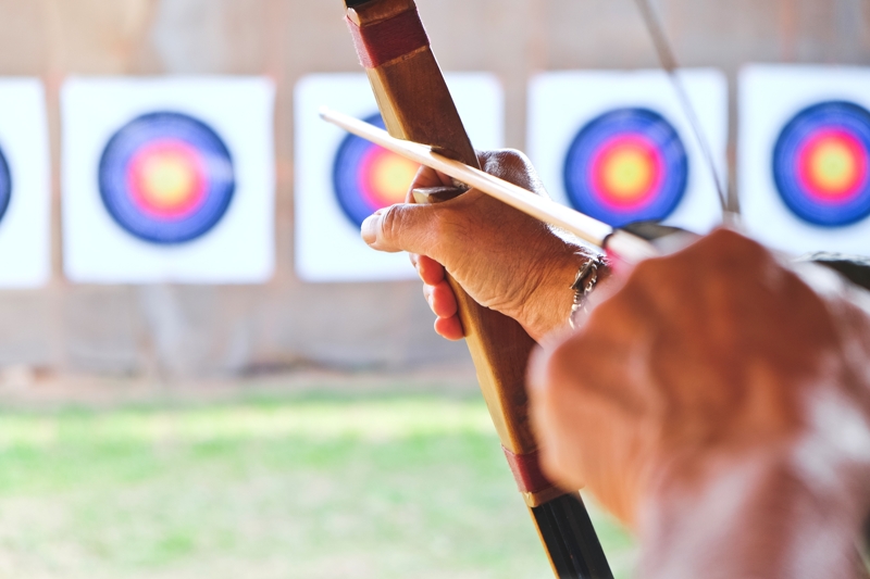 A archer holds their bow while aiming at a target.