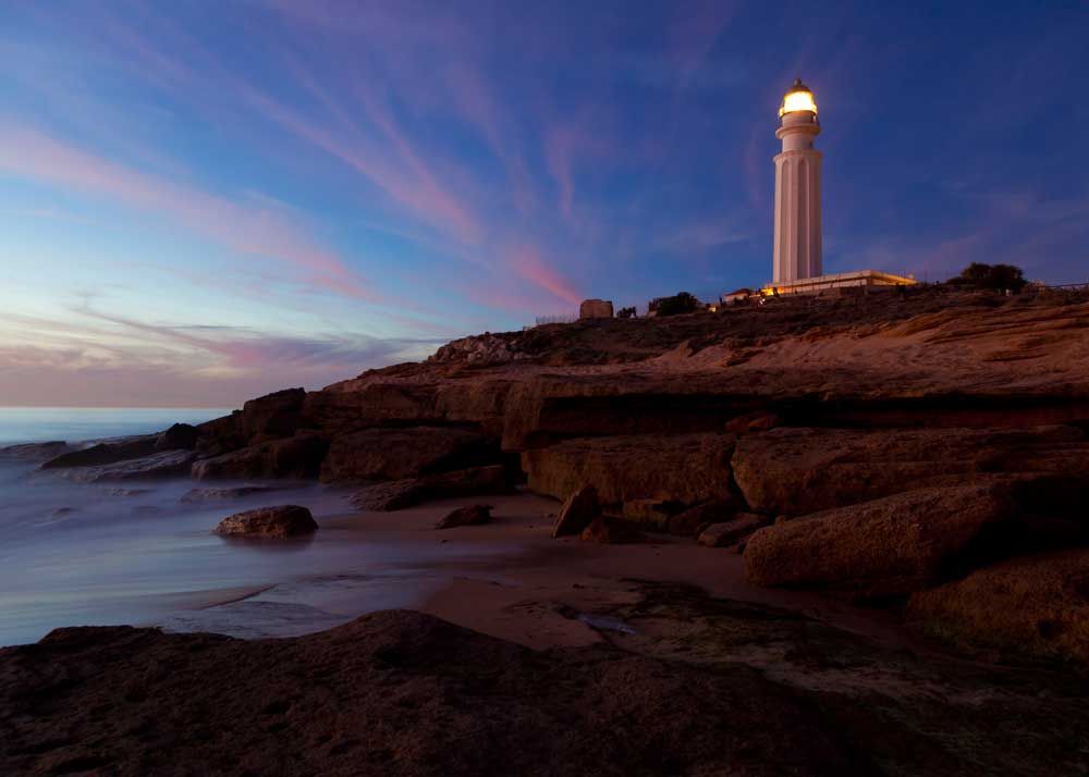 A lighthouse lighting the way near a rocky coastline